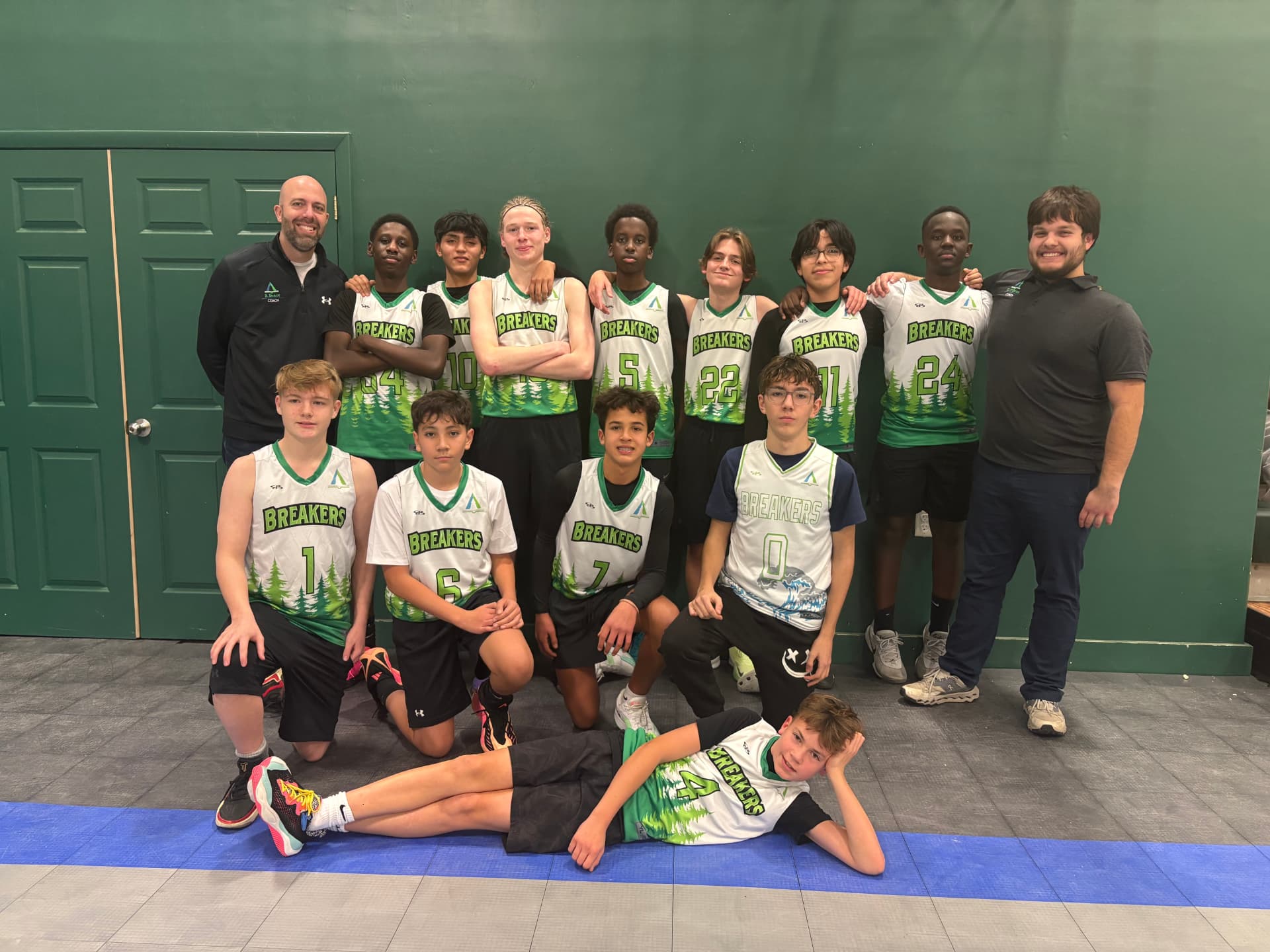 Pine Tree Academy boys JV basketball team and coaches posing together in the school gym
