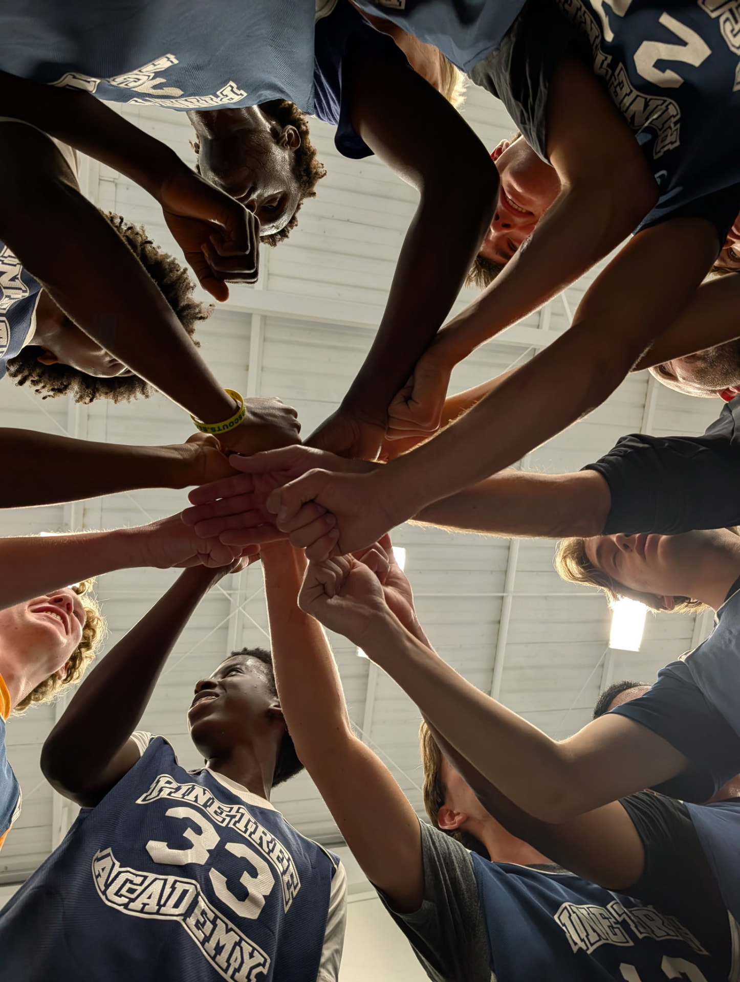 Pine Tree Academy basketball players joining hands in a pre-game huddle during Alumni Weekend