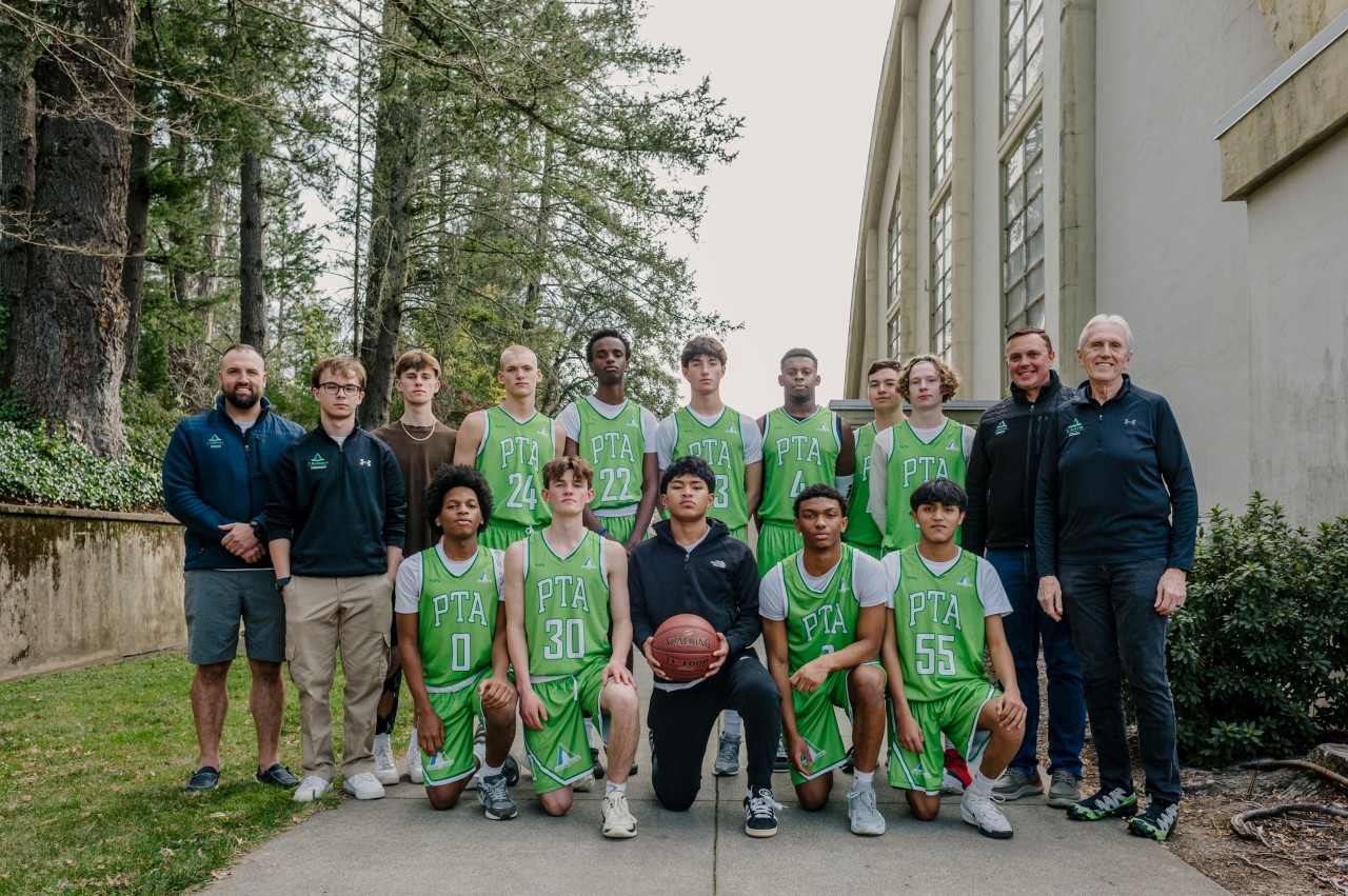 Pine Tree Academy boys varsity basketball team and coaches posing together at the Pacific Union College Tournament in California