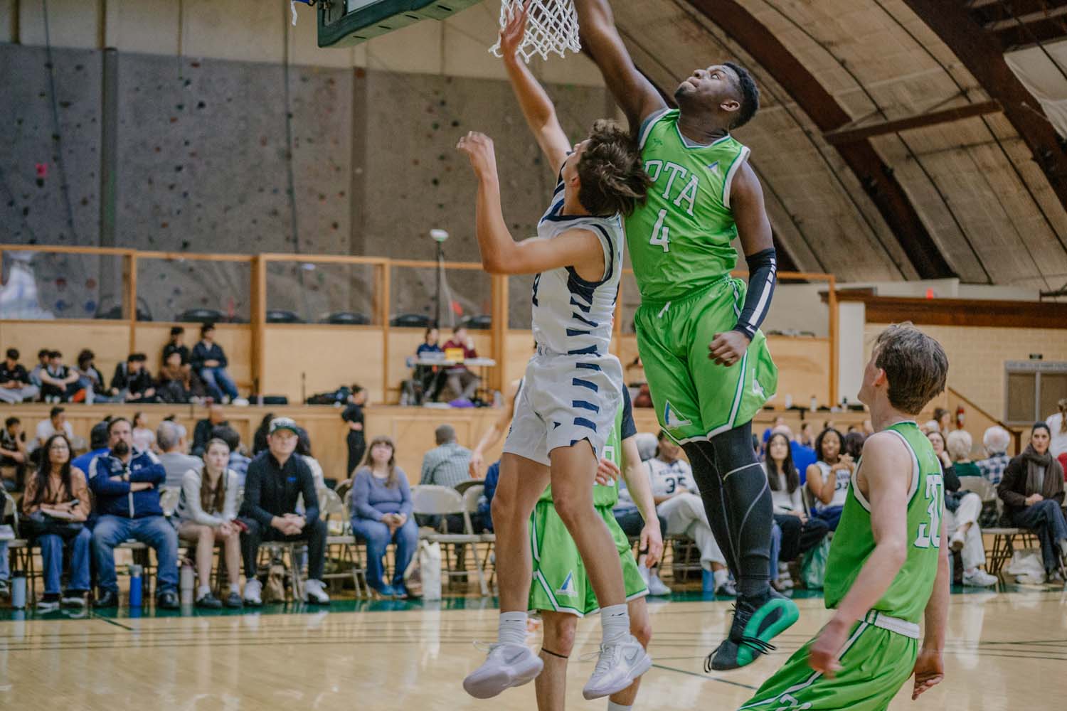 Pine Tree Academy boys varsity basketball player in a green uniform rising to finish at the rim at the Pacific Union College Tournament