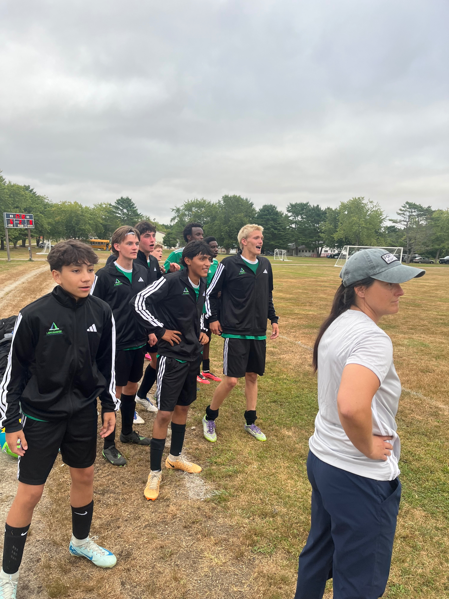 Pine Tree Academy boys varsity soccer players and Coach Remmes-Davis on the sideline during the 6-0 home win over Dirigo High School
