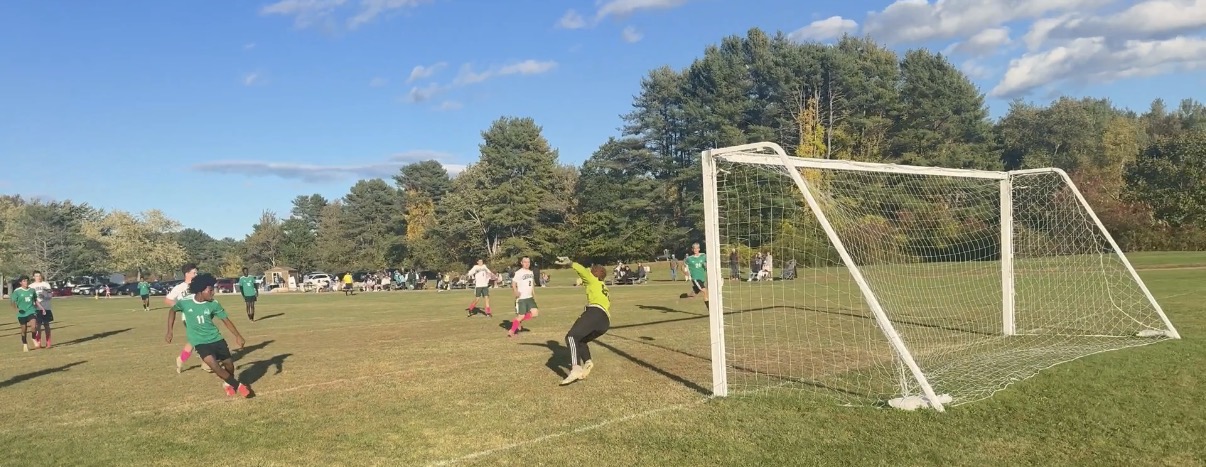 Pine Tree Academy attacker shoots as the Carrabec/Madison goalkeeper dives during the October 9, 2026 match in Freeport