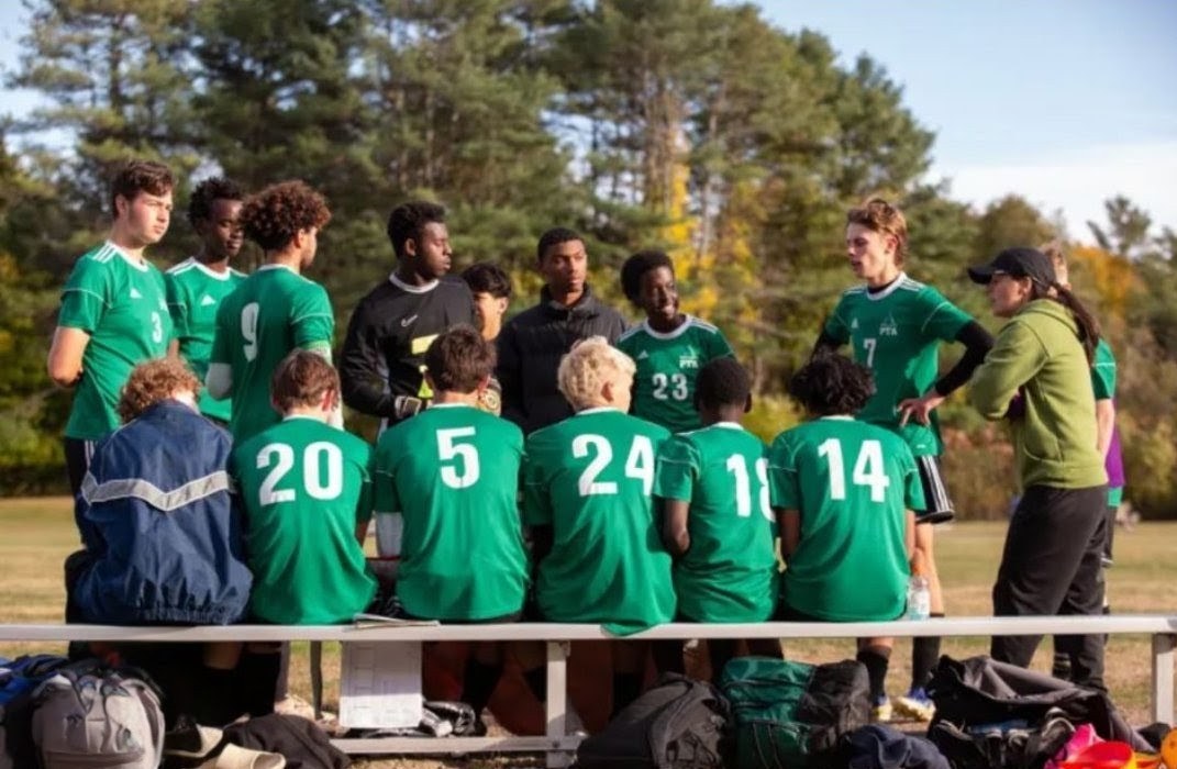 Pine Tree Academy boys varsity soccer players and coaches huddled together on the sideline