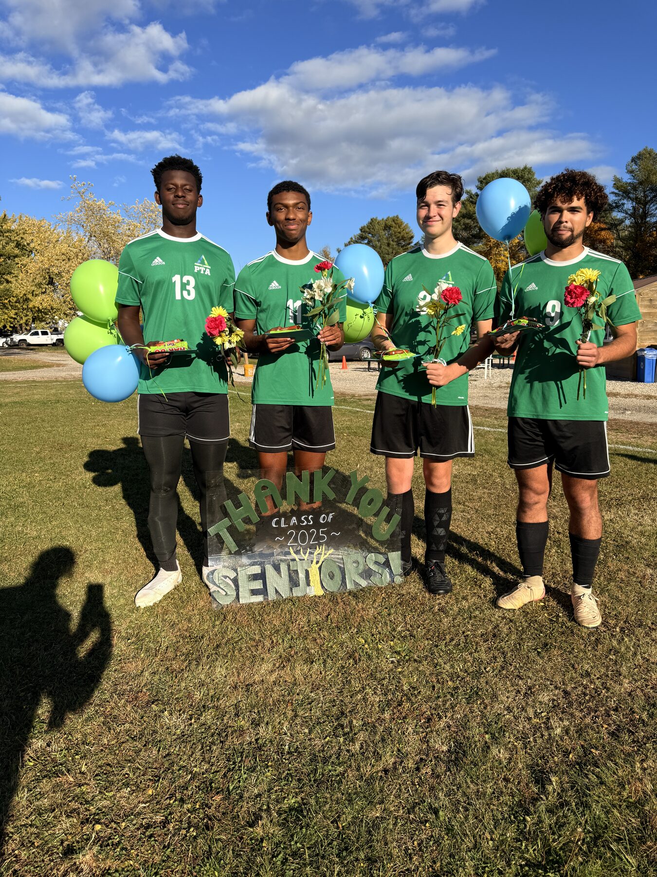 Pine Tree Academy boys soccer seniors standing together with flowers and balloons on senior night