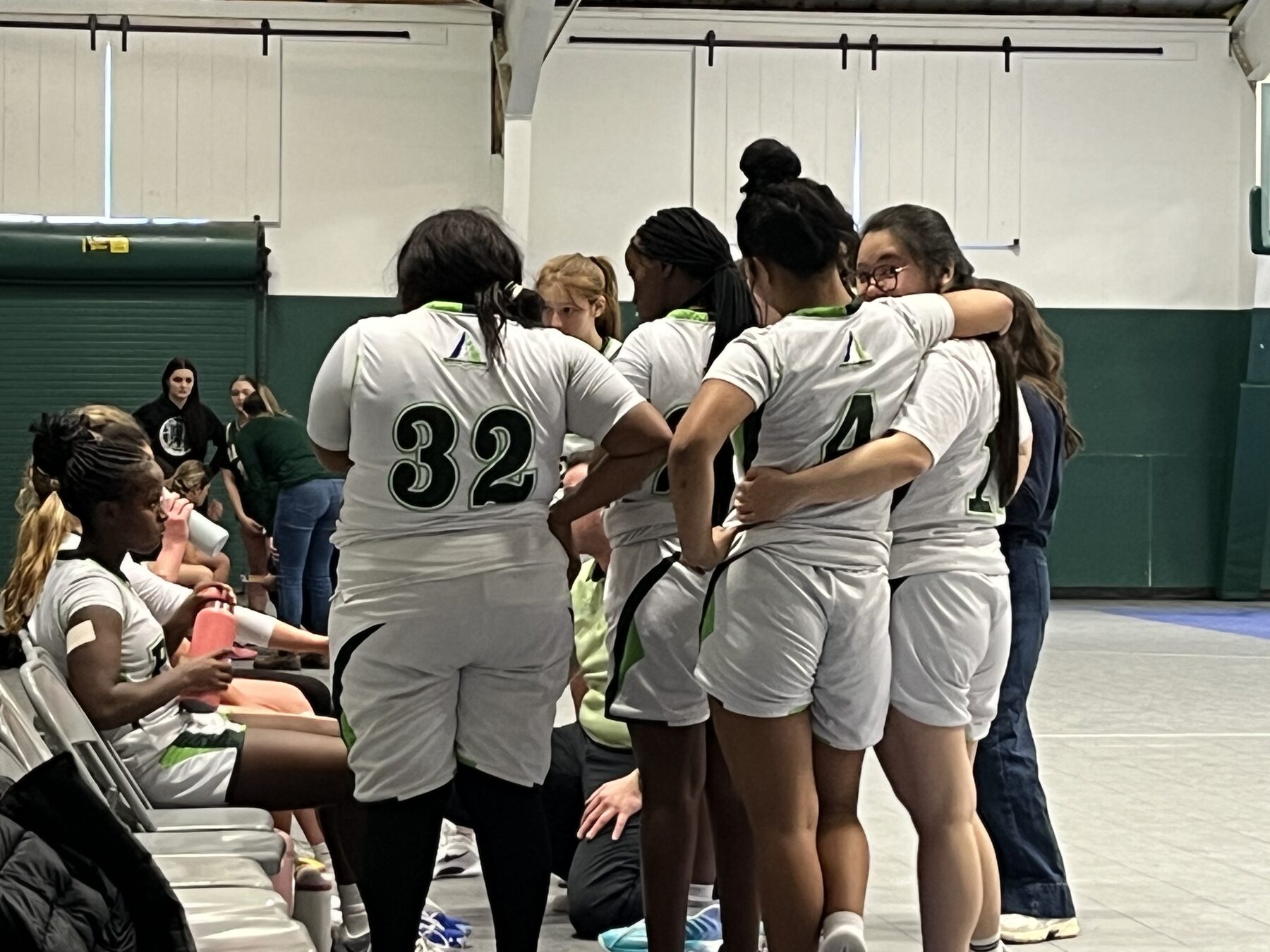 Pine Tree Academy girls varsity basketball team gathered together in a huddle