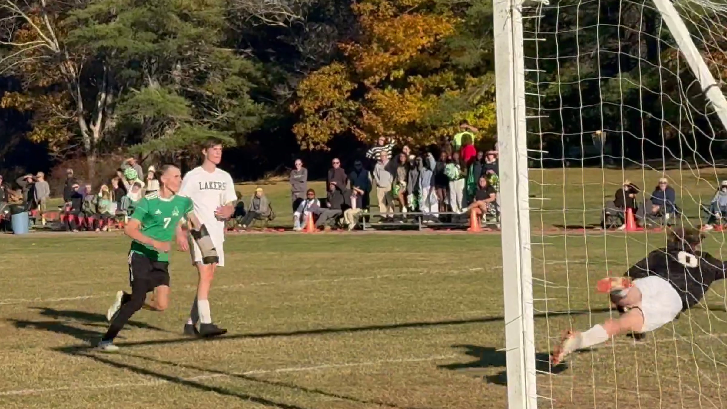 A Pine Tree Academy player in green near the goal as Rangeley's goalkeeper dives across the goalmouth during the 5–0 quarterfinal win