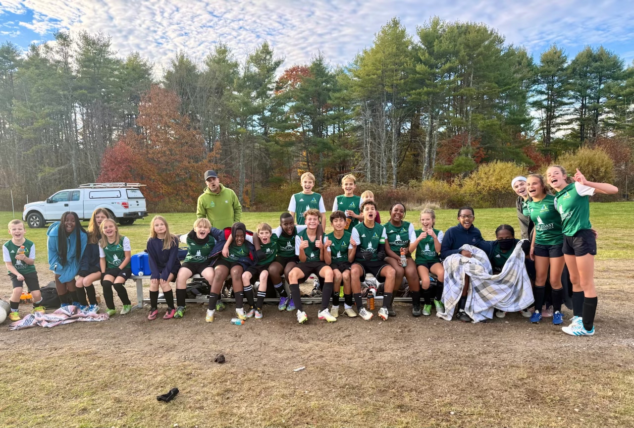 Pine Tree Academy middle school soccer players celebrating together on the sideline.