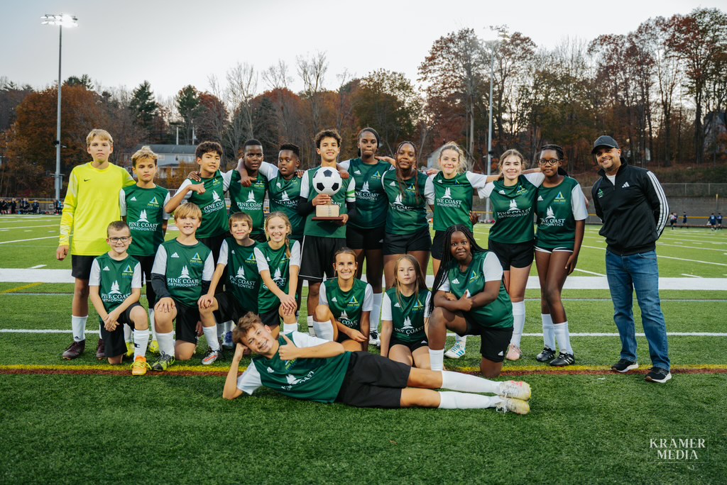 Pine Tree Academy middle school soccer players posing with the 2026 MCSSL championship trophy on the field.