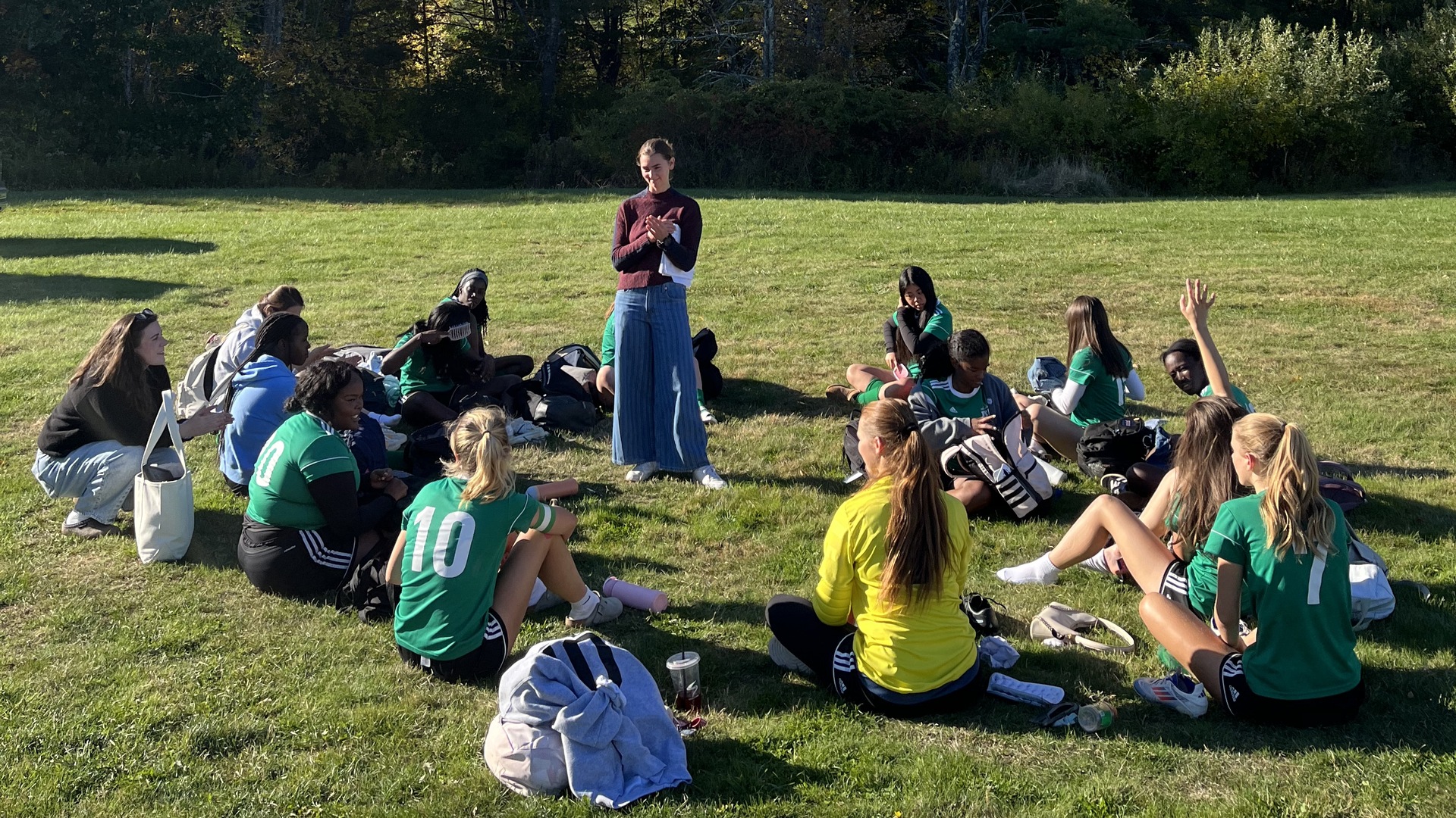 Pine Tree Academy girls varsity soccer players gather on the grass with their coach during the October 9, 2026 home game against Carrabec
