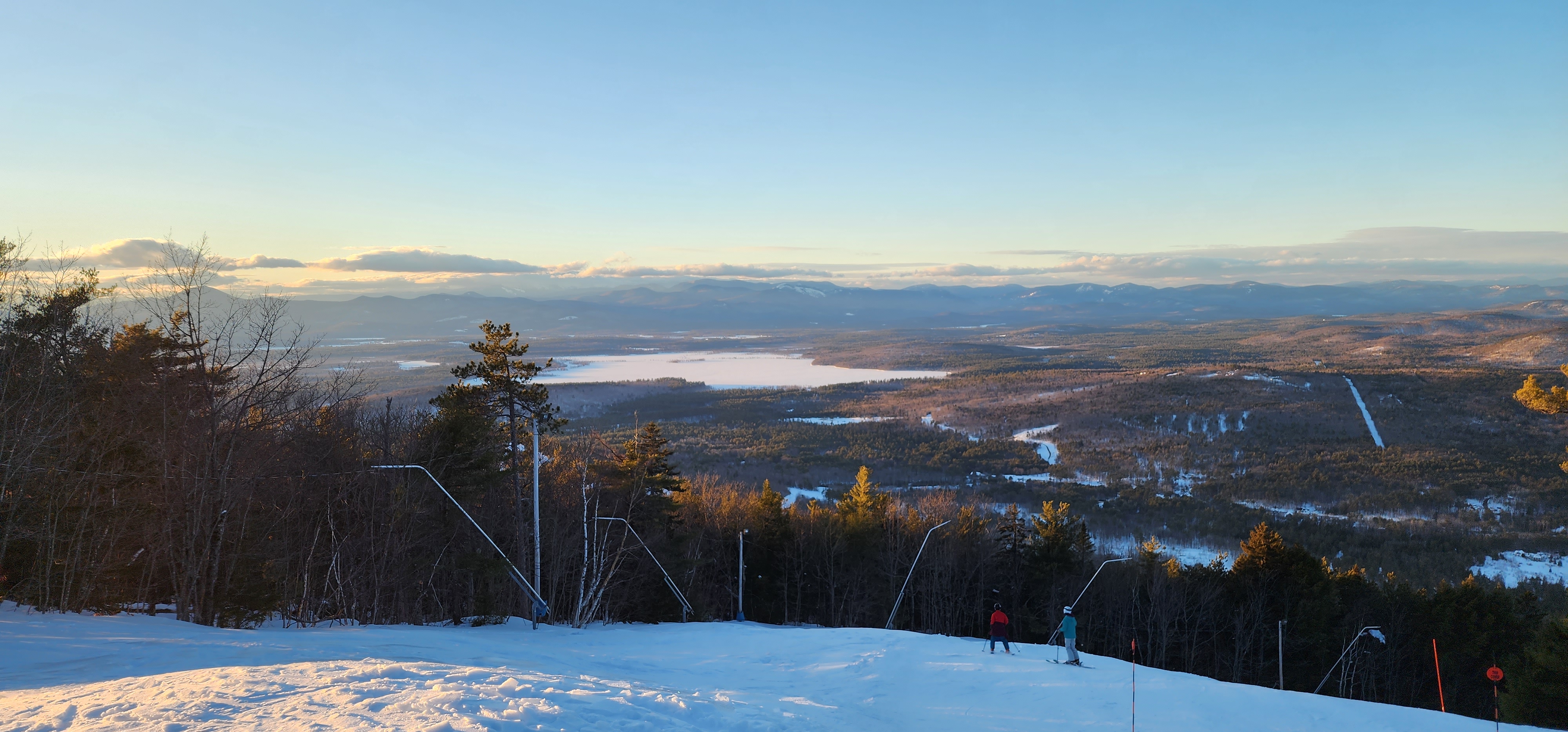 A skier descending a sunlit trail with a mountain valley beyond during the PTA Snowsports program