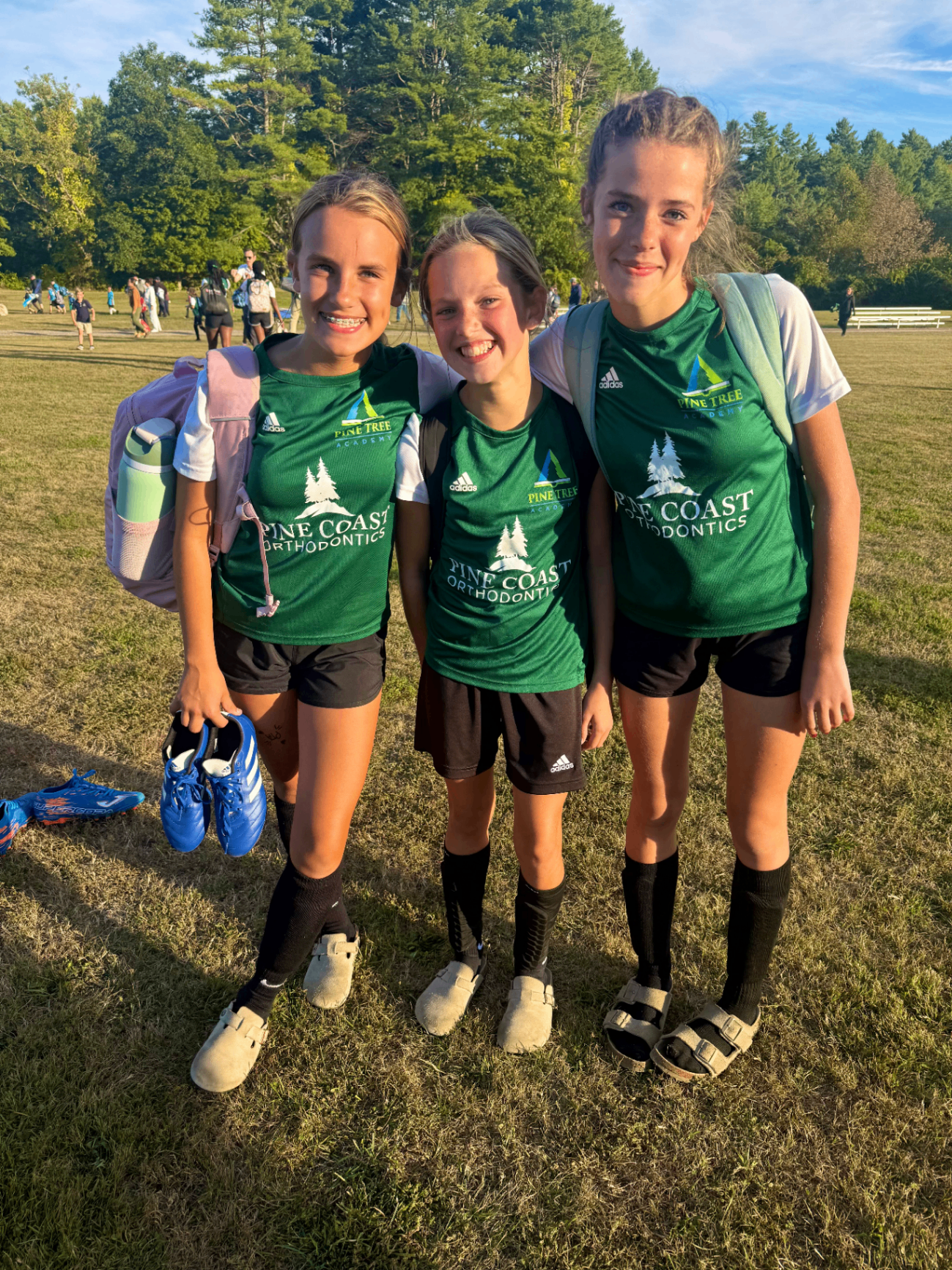 Three Pine Tree Academy middle school soccer players in green Breakers uniforms smiling together on the field after the 7-3 road win over Windham Christian Academy